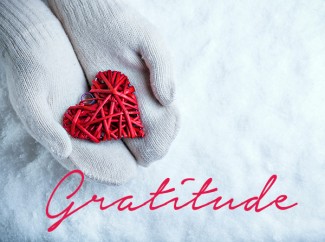 hands with white mittens holding red heart and snow background