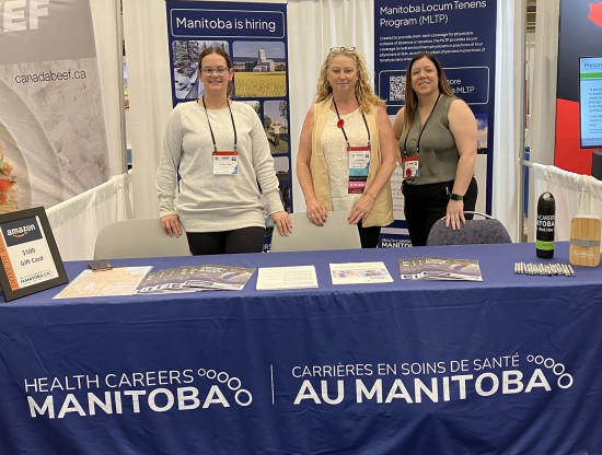 Three employees standing behind a career fair booth