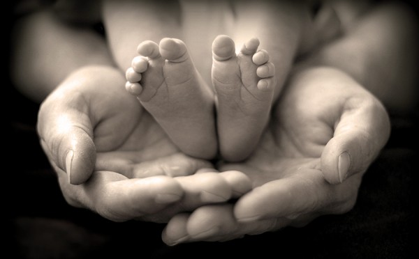 mains de parents tenant les pieds de bébé