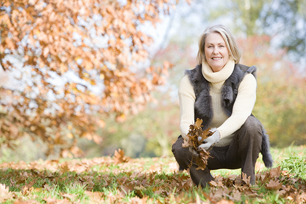 Elderly woman kneeling outside holding leaves