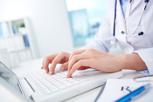 medical professional entering data on laptop